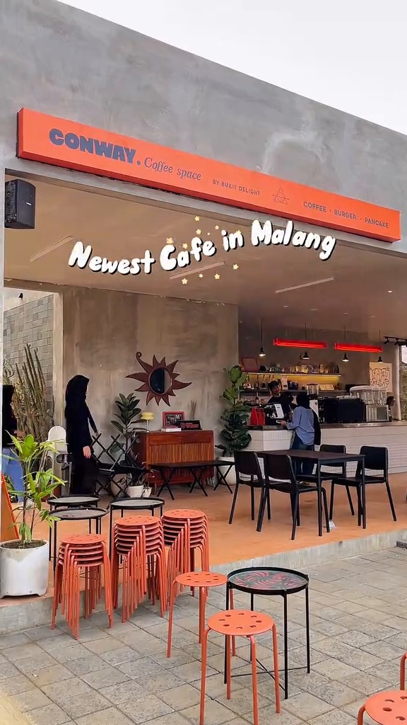 Meja-meja di area semi-outdoor CONWAY dengan atap dan pencahayaan sore hari