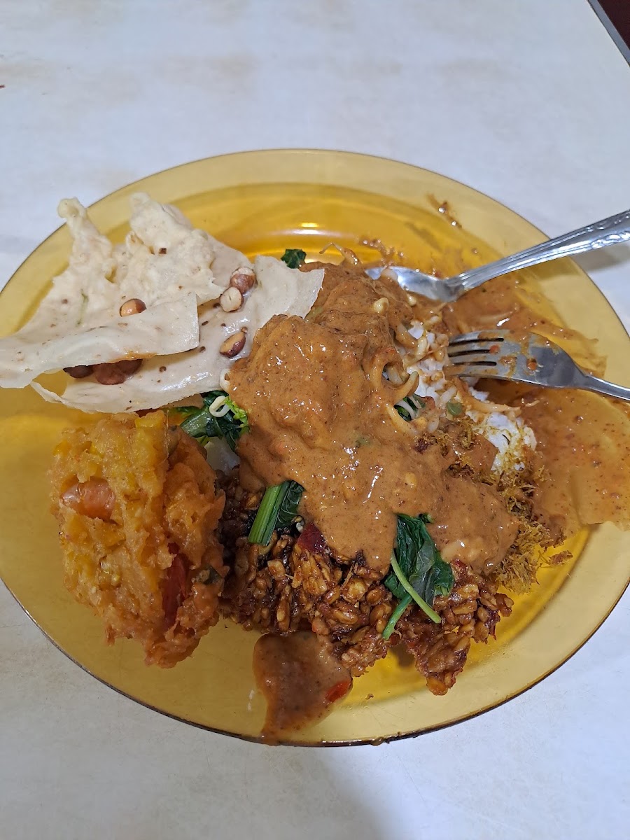 Sepiring nasi kare ayam kampung berkuah santan kuning dengan potongan ayam dan kerupuk.