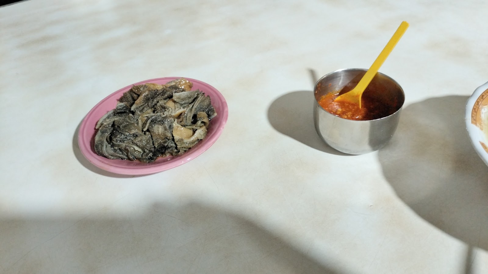 Sepiring sayur pecel hijau di meja marmer, ditemani mangkuk kecil berisi sambal kacang.
